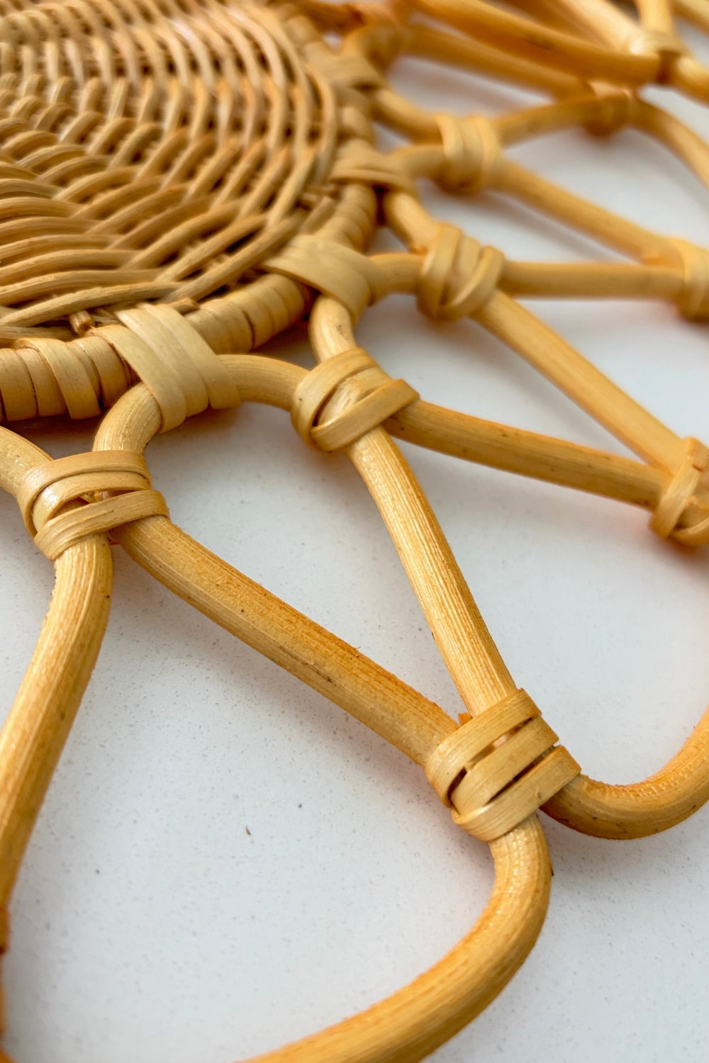 Close-up of the circular woven center and radiating looped arms on the natural beige rattan placemat by Matisa Deco.