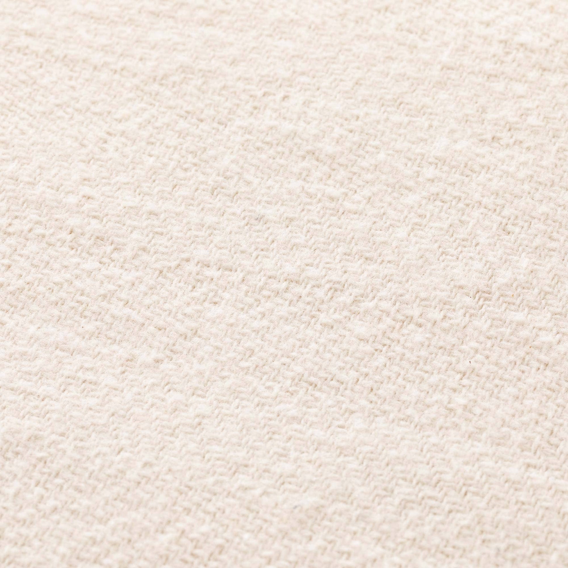 Close-up of the breathable ecru cotton fabric texture on the NATURE collection fringed throw.