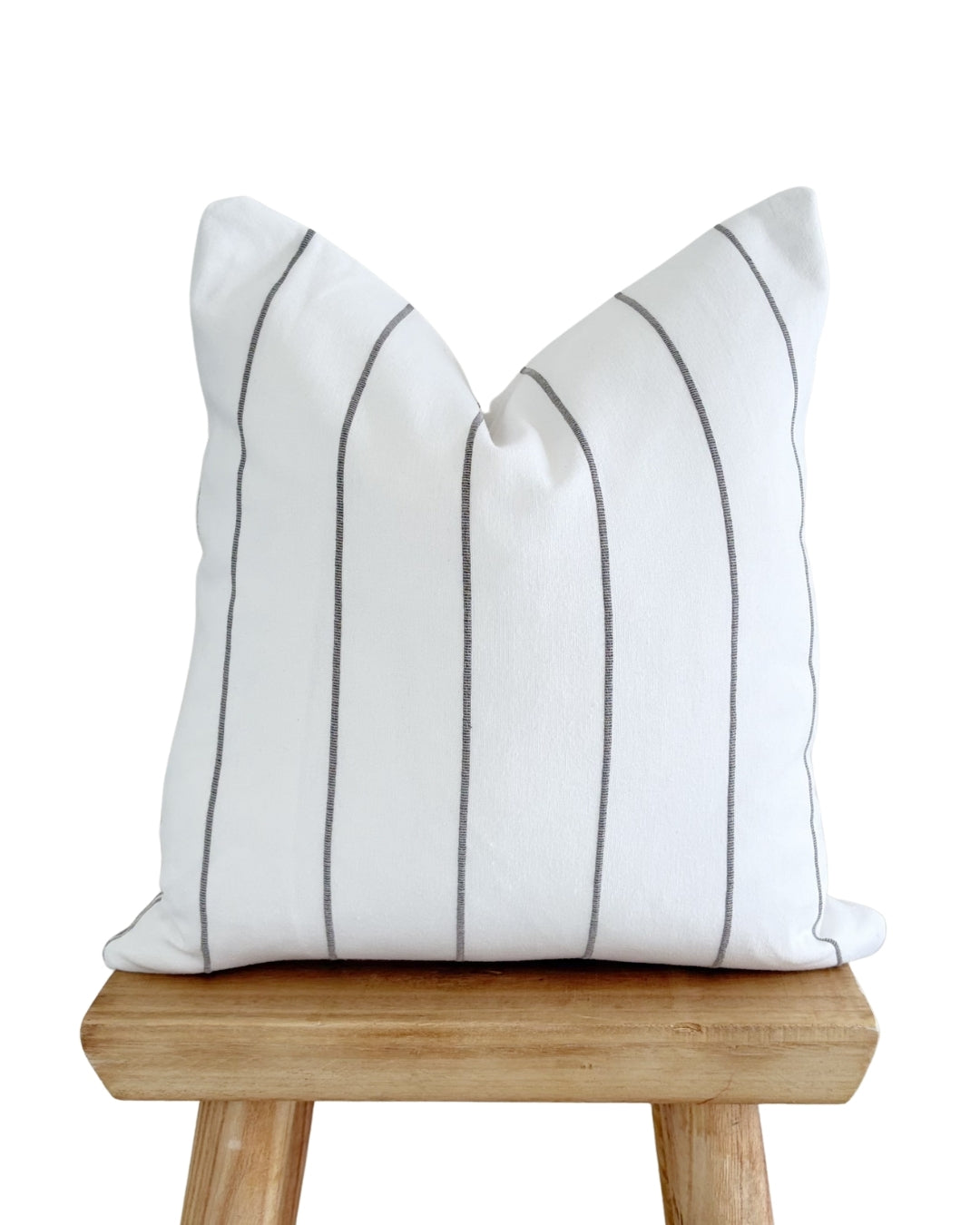 Flax white and brown textured cushion cover styled on a rustic wooden stool.