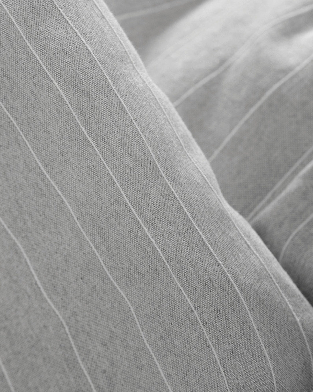 Close-up Detailed view of the fine white linear stripes on grey jacquard cotton fabric.