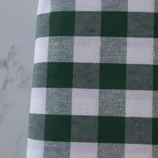 Close up video of green and cream gingham tablecloth highlighting its cotton rich woven texture, checked pattern and fabric finish.