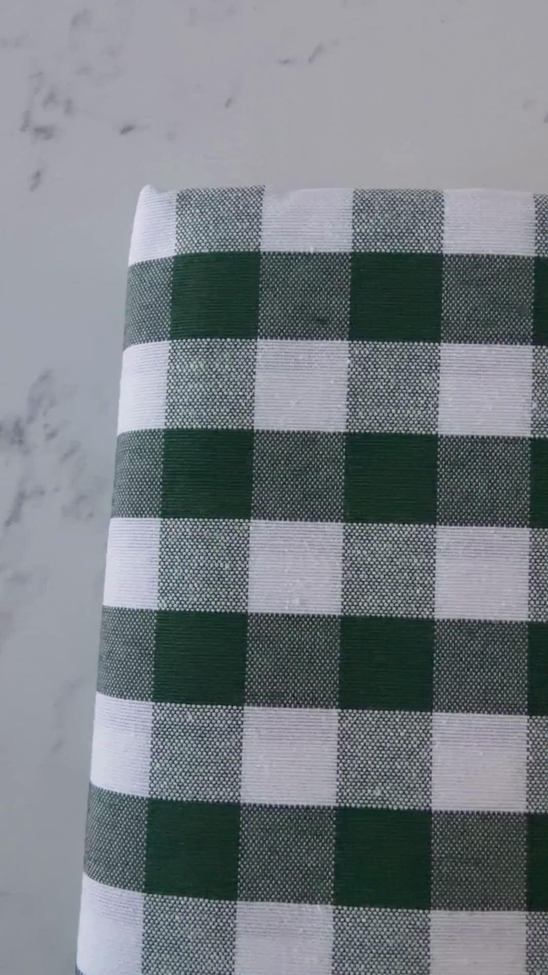 Close up video of green and cream gingham tablecloth highlighting its cotton rich woven texture, checked pattern and fabric finish.