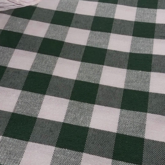 Green gingham water repellent tablecloth demonstration showing water beading on the fabric and being wiped away.
