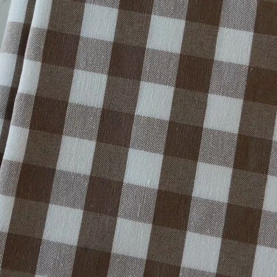 Close up video of taupe and cream gingham tablecloth highlighting its cotton rich woven texture, checked pattern and fabric finish.