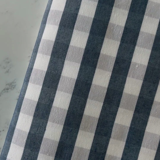 Close up video of navy blue and cream gingham tablecloth highlighting its cotton rich woven texture, checked pattern and fabric finish.