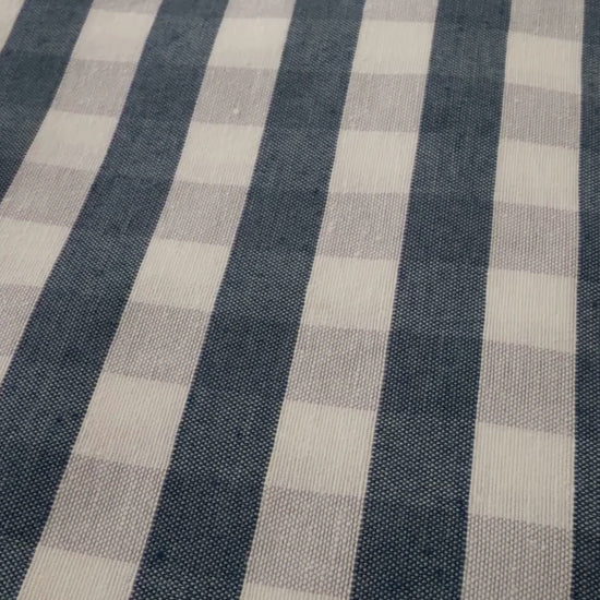 Navy blue gingham water repellent tablecloth demonstration showing water beading on the fabric and being wiped away.