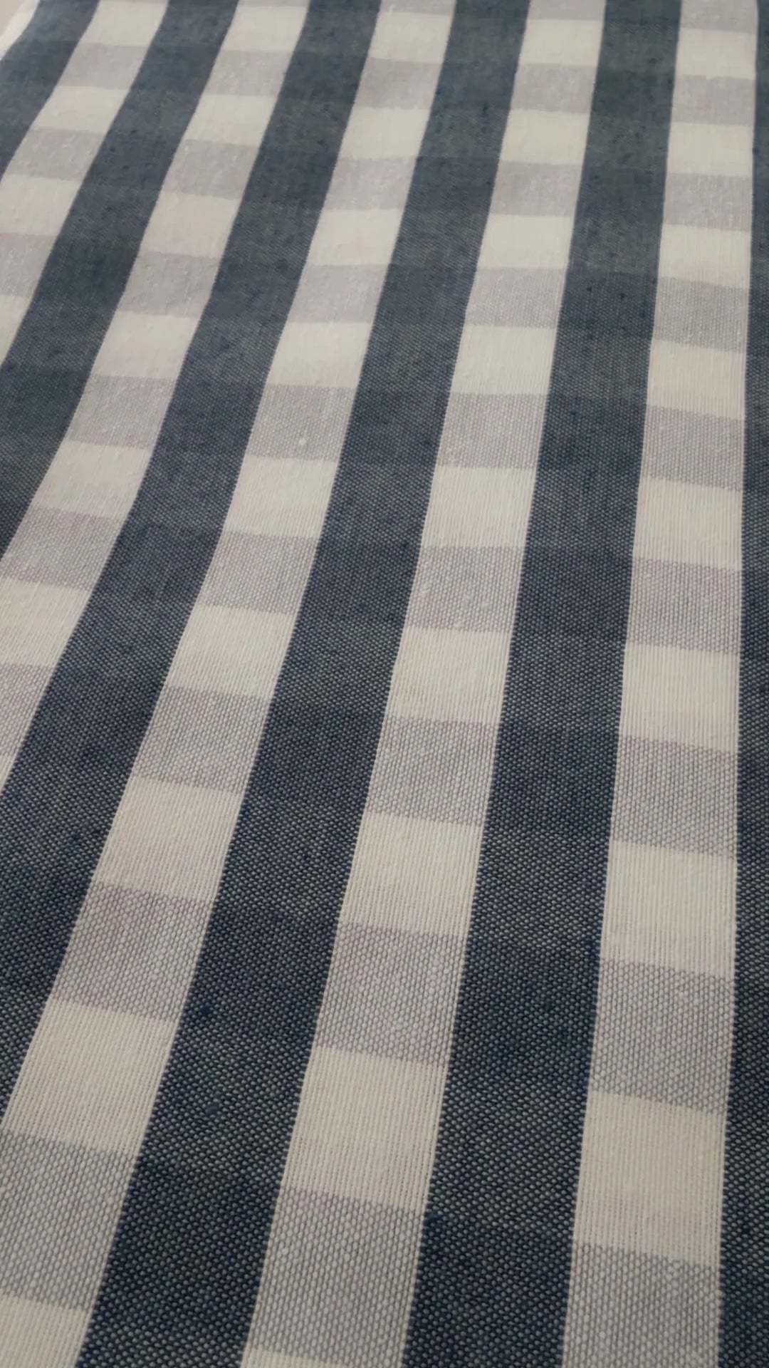 Navy blue gingham water repellent tablecloth demonstration showing water beading on the fabric and being wiped away.
