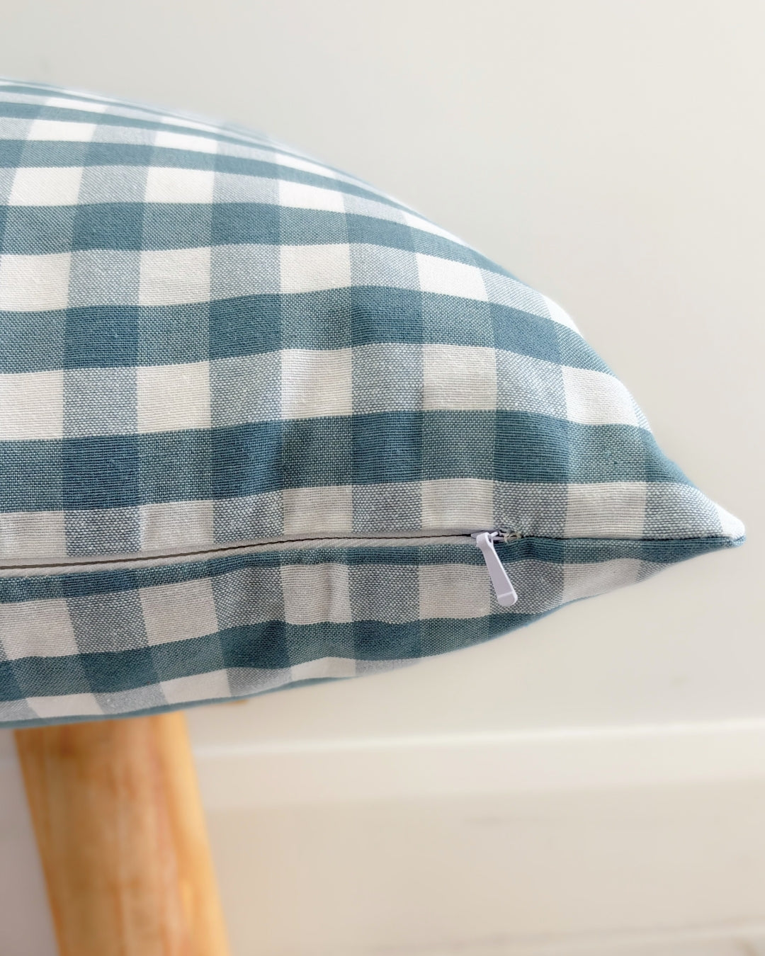Green and white checkered pillow on a wooden stand against a light background