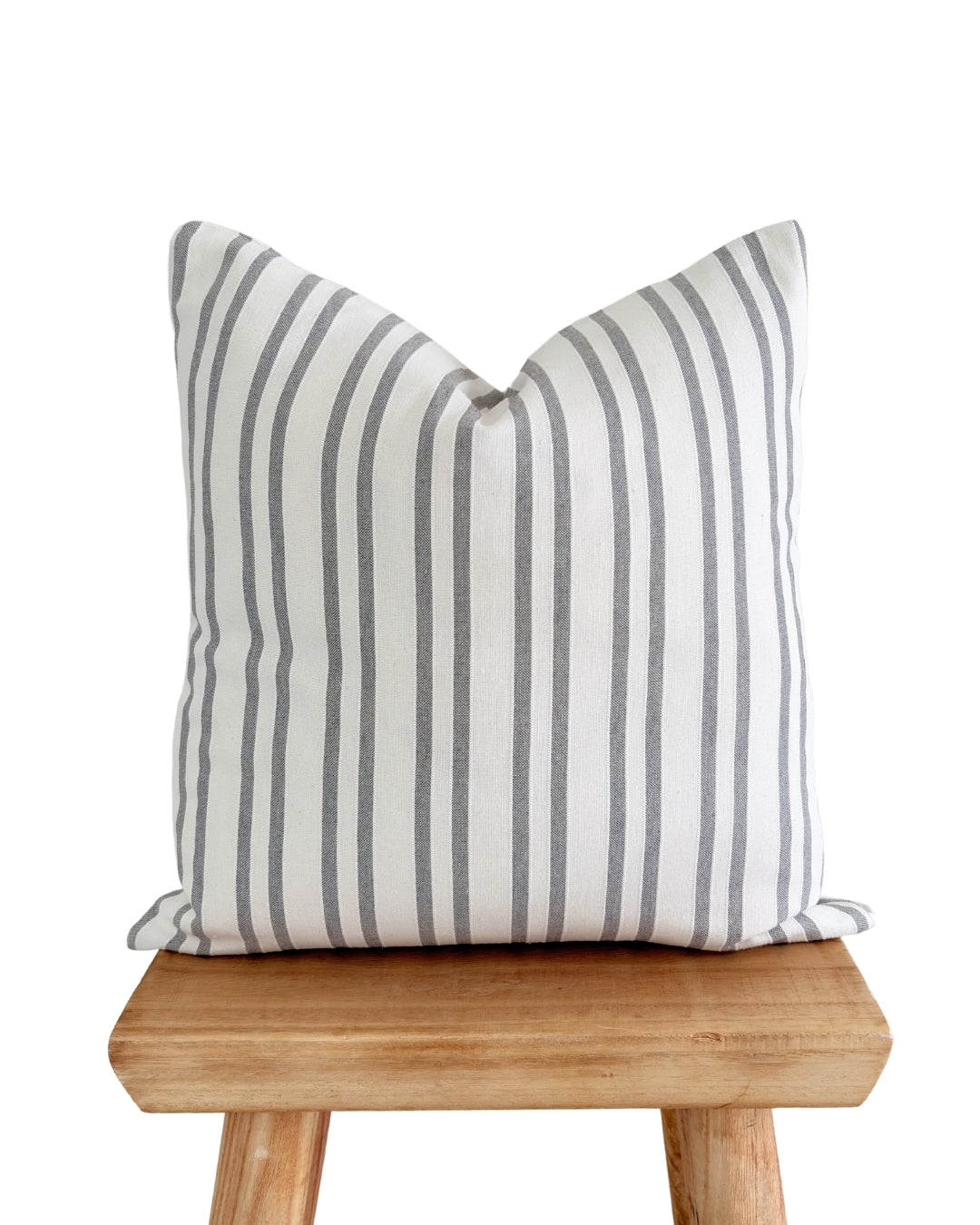 taupe linen jacquard cushion cover styled on a rustic wood stool.