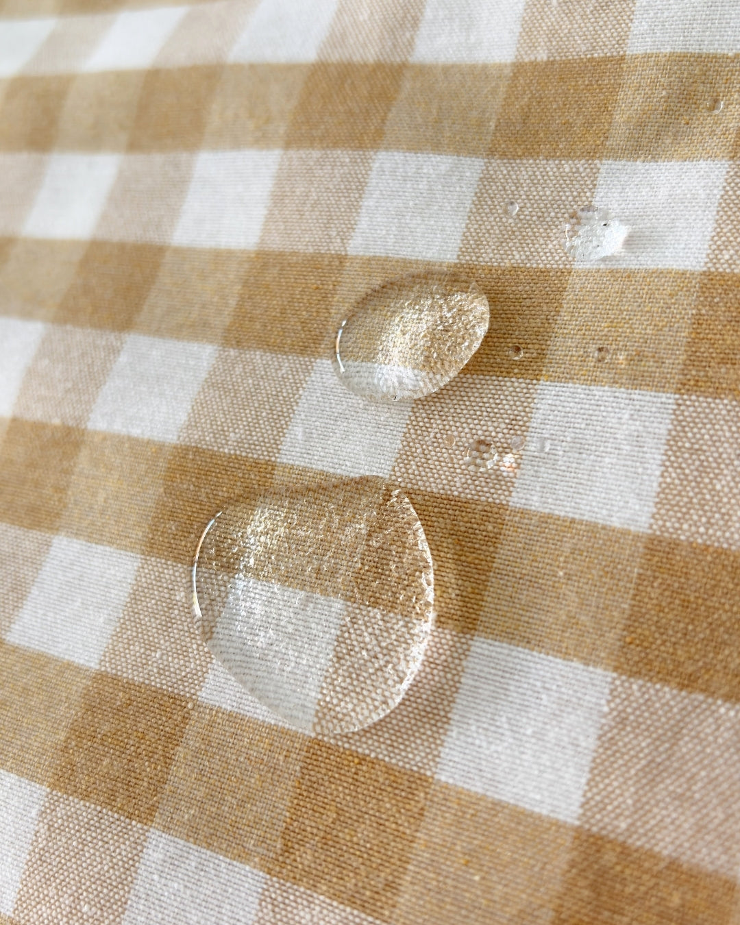 Close-up of water-beading effect on beige water-repellent finish fabric.