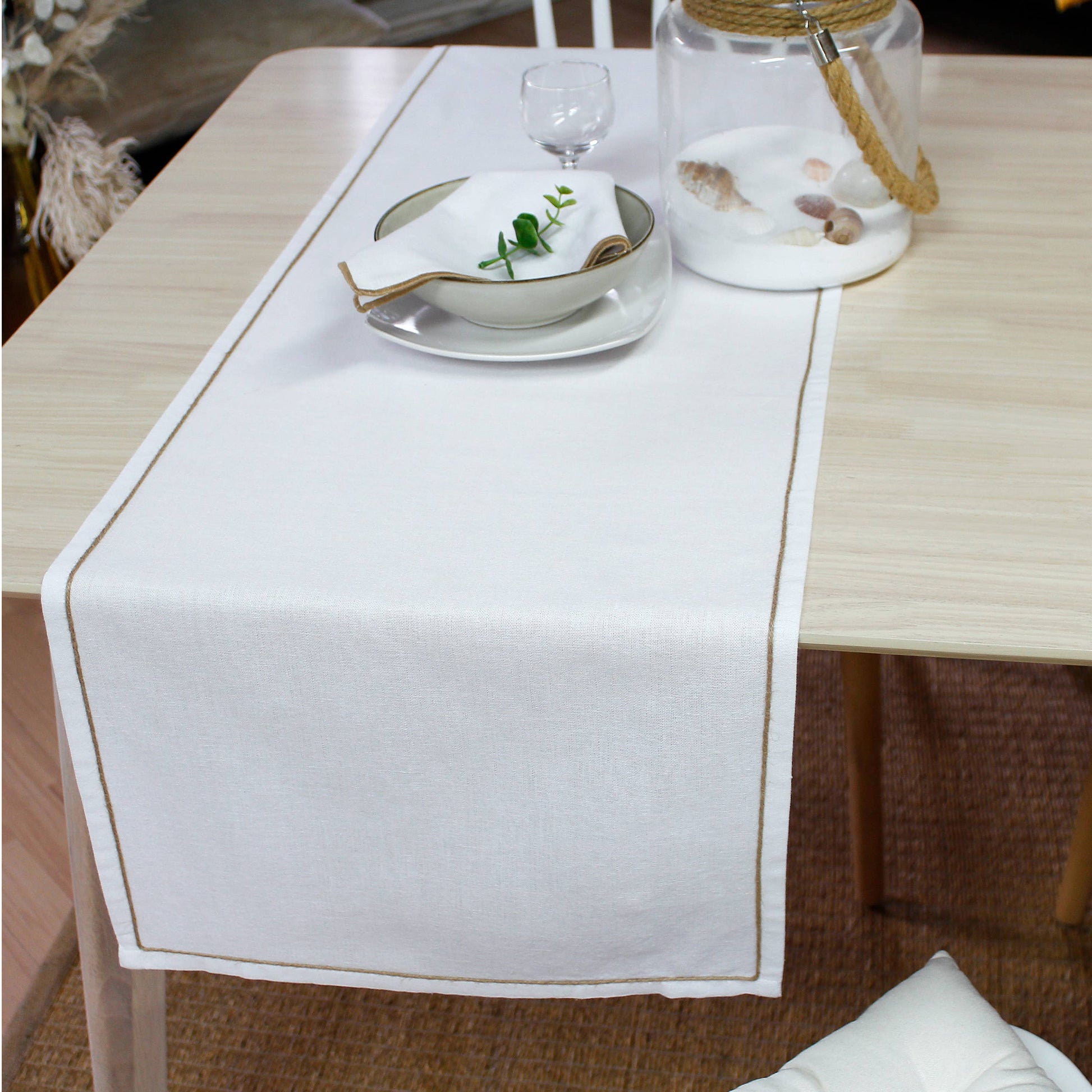 Close up of the water repellent effect on a white textured runner showing the artisanal jute festoon border.